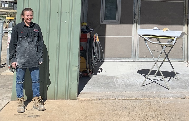 Young tradeswoman in work wear outside work building.