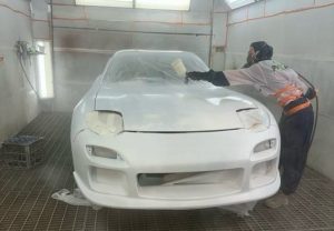 Female auto spray painter spraying a car.