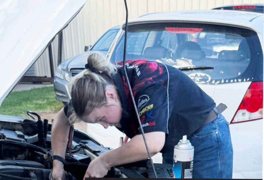 Young woman working on a car as an auto apprentice